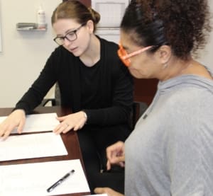 Two students looking at three printed lists of terms on a table.
