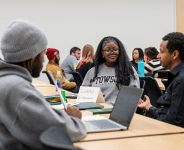 Three MD HIRES Students and Faculty from Towson University are in a classroom and engaging in a conversation about the authorship of scientific papers.